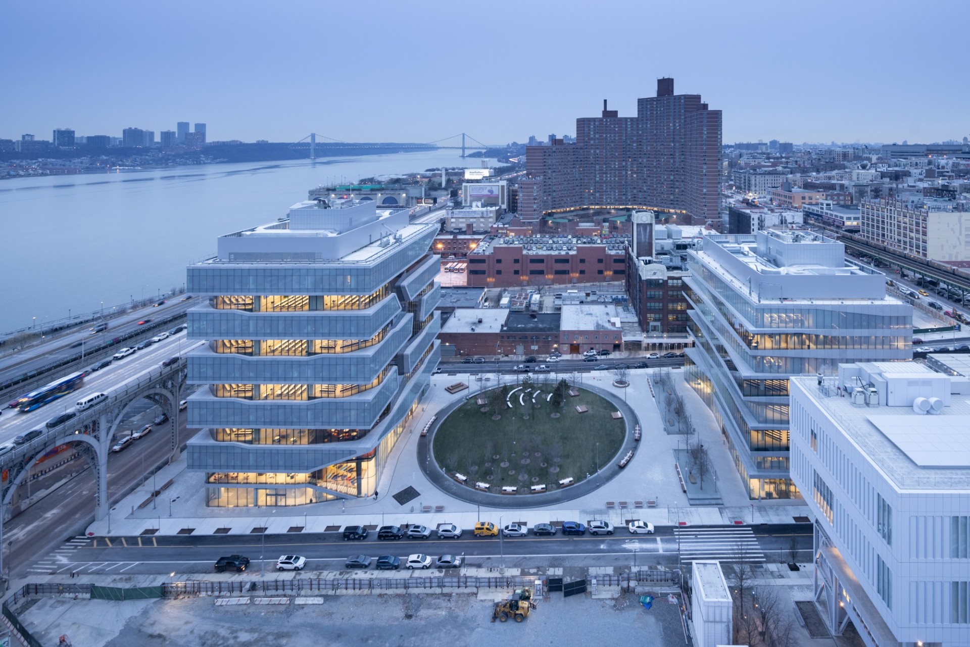 An aerial view of the new Columbia Business School building, looking north, with a bunch of buildings in the background and the Hudson River to the west.