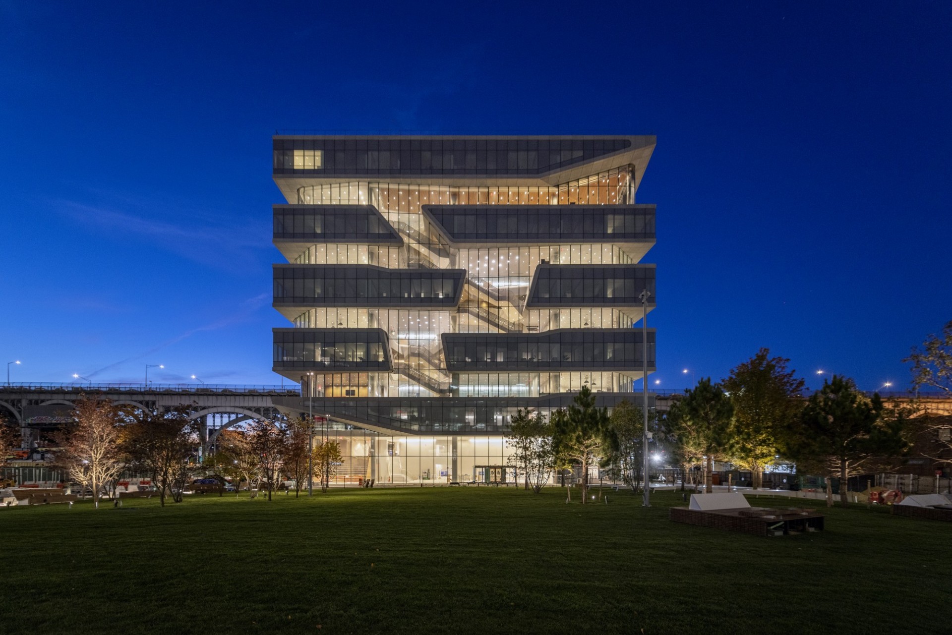 A view of Henry R. Kravis Hall during the evening, illuminated by interior lights.