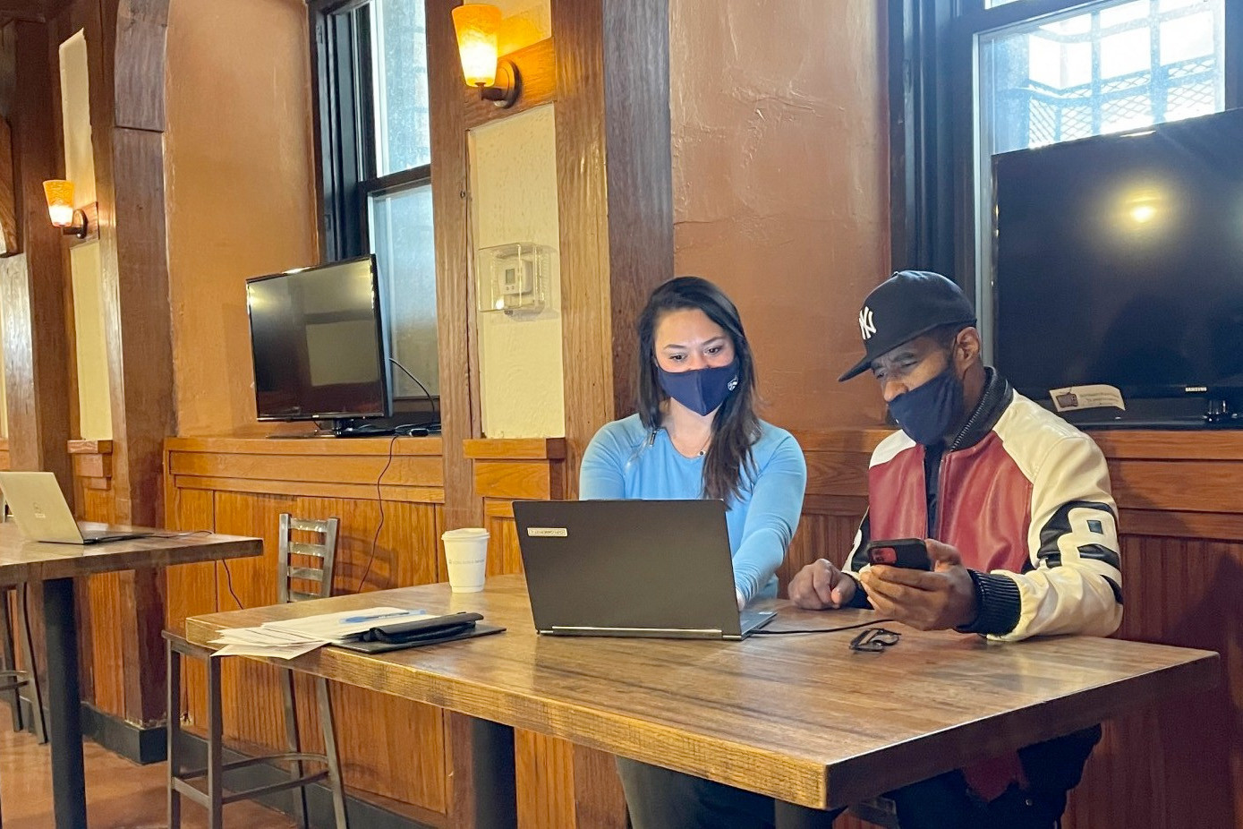 A Facilities and Operations HR representative stands next to a prospective employee, looking at a laptop in John Jay Hall.