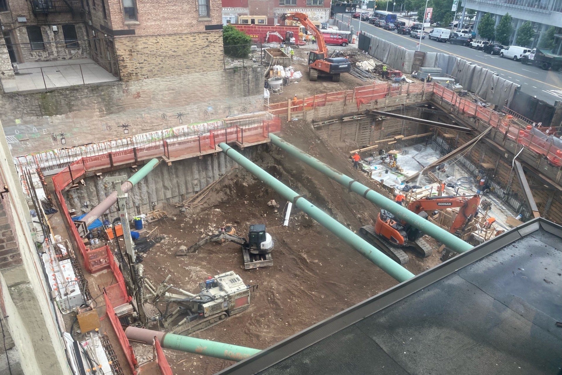 A new 34-story residential building is being constructed on the corner of 125th Street and Broadway. An excavated pit with large green pipes running overhead at the 600 W. 125th Street construction site.
