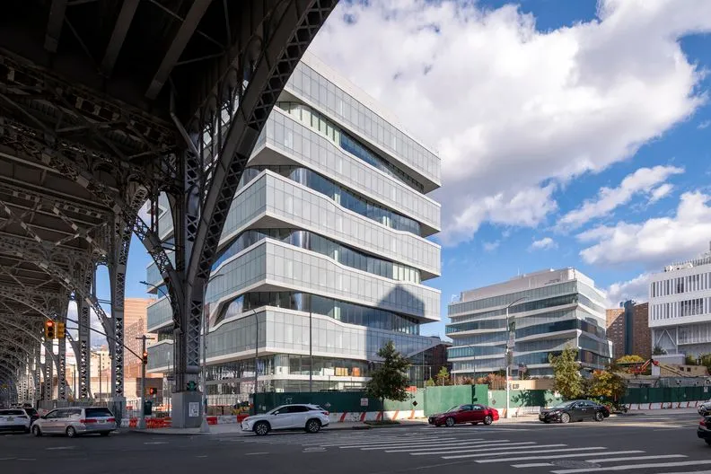 A view of Henry R. Kravis Hall and David Geffen Hall from underneath the viaduct on a sunny day.