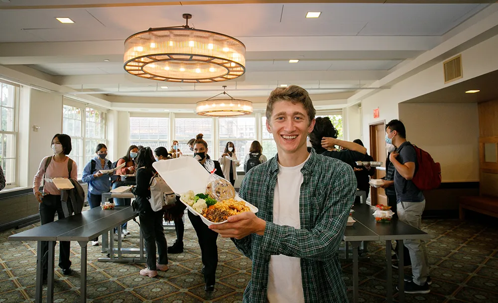 A smiling student shows off their lunch