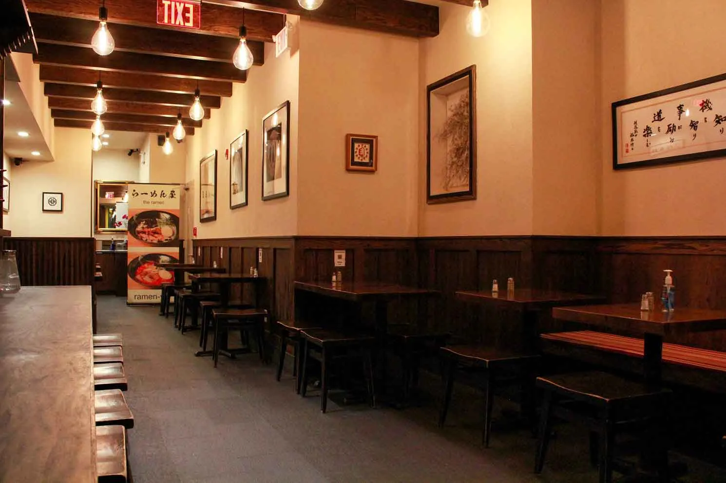 The interior of Ramen Kuraku, which has wooden panels on the walls, with wooden tables situated against the wall.